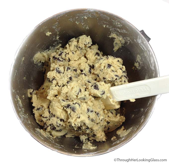 a metal mixing bowl filled with chocolate chip cookie dough