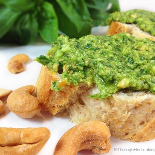 this easy cashew basil pesto spread on a piece of bread with roasted cashews in the foreground