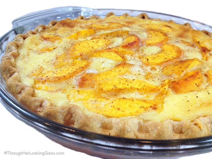 a whole, unsliced peach custard pie in a glass pie dish