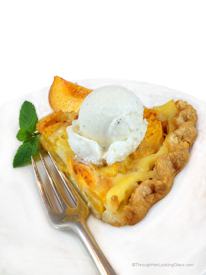 a slice of Peach custard pie on a white plate with a scoop of vanilla ice cream on top