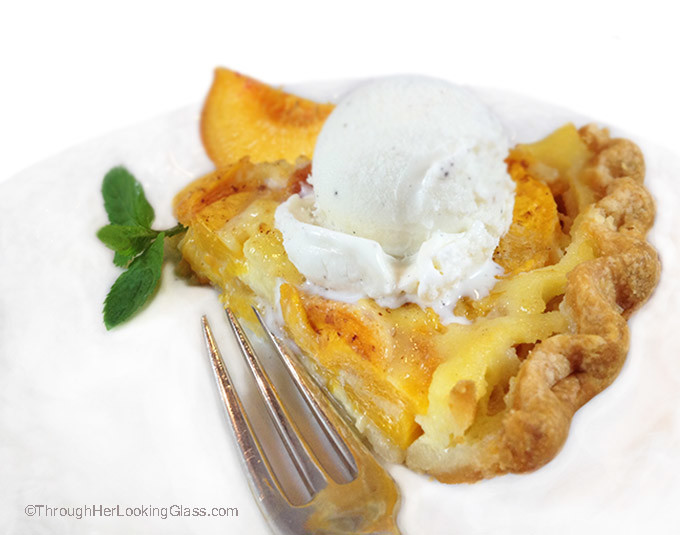 Peach custard pie on a white plate with a scoop of vanilla ice cream on top