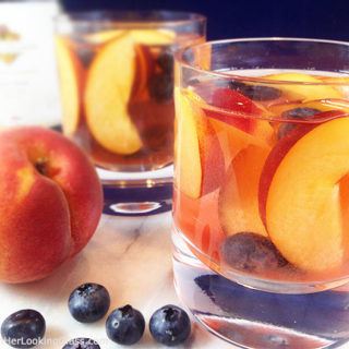 Easy and fruity: Make White Wine Peach Sangria by the pitcherful! Sweet peaches macerate in a delicious cocktail for all the pool & patio summer parties!