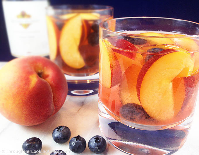 Easy and fruity: Make White Wine Peach Sangria by the pitcherful! Sweet peaches macerate in a delicious cocktail for all the pool & patio summer parties!