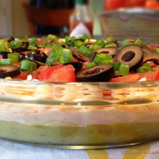 San Francisco Layer Dip: zippy guacamole dip with greek yogurt, taco seasoning, cheese, tomatoes, olives, green onions and hot pepper sauce.