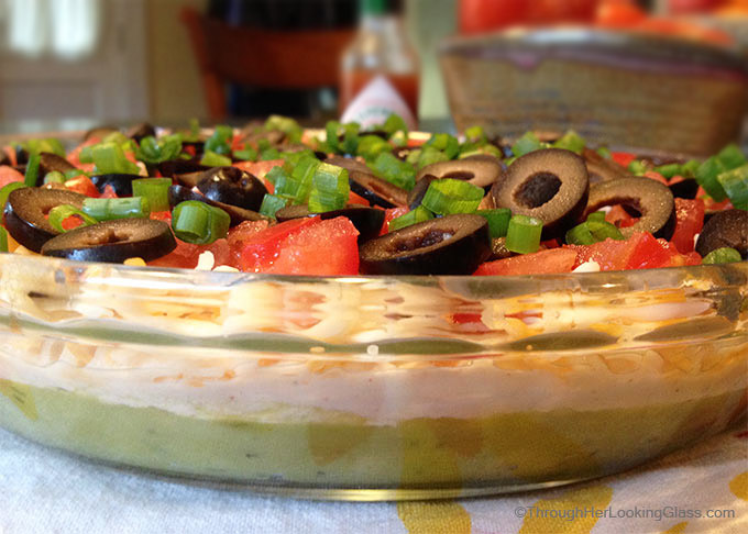 San Francisco Layer Dip: zippy guacamole dip with greek yogurt, taco seasoning, cheese, tomatoes, olives, green onions and hot pepper sauce.