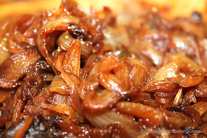 a closeup of slow-cooked golden brown caramelized onions with balsamic vinegar in a skillet