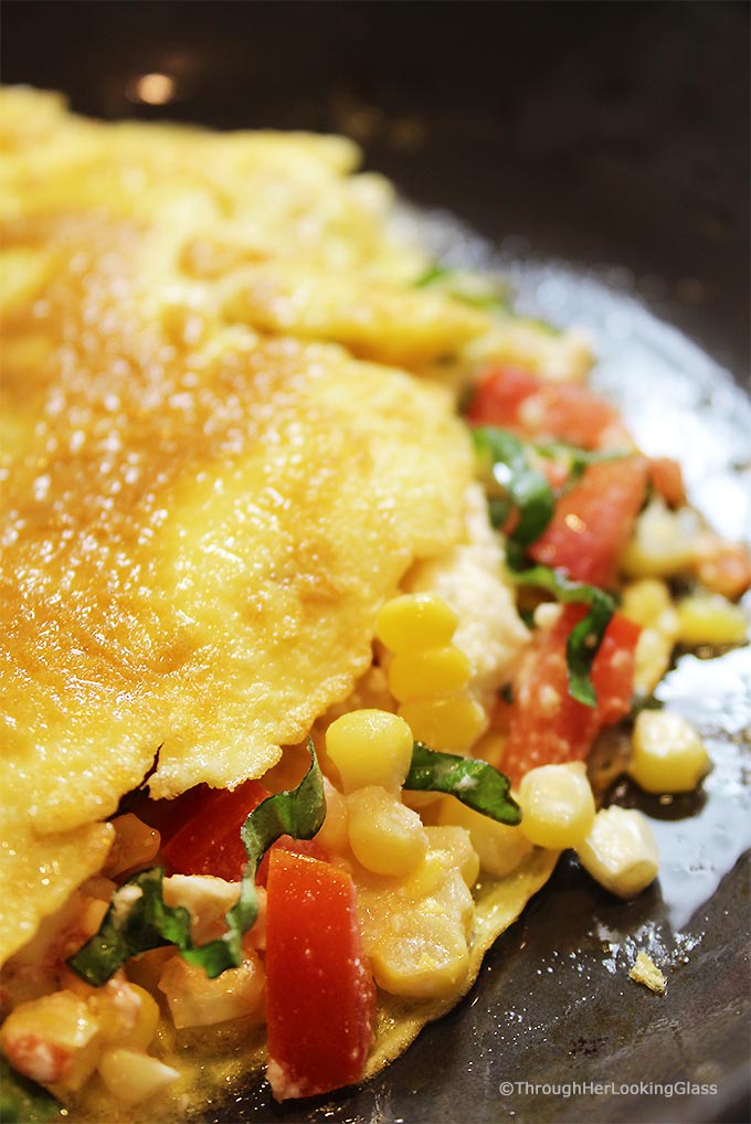 This Summer Corn Basil Tomato & Feta Easy Omelette Recipe is sure to please your friends and family for breakfast, lunch or dinner. Summer corn and juicy, ripe tomatoes combine with fresh garden basil and salty feta for a flavor-full omelette.