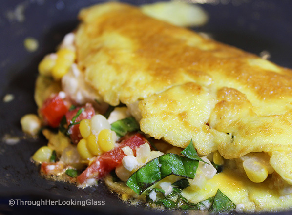 This Summer Corn Basil Tomato & Feta Easy Omelette Recipe is sure to please your friends and family for breakfast, lunch or dinner. Summer corn and juicy, ripe tomatoes combine with fresh garden basil and salty feta for a flavor-full omelette.