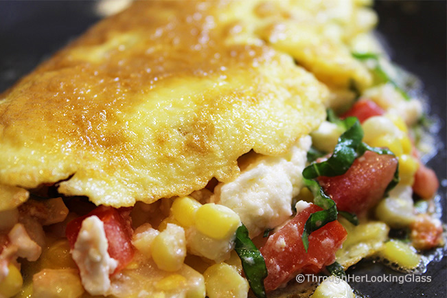 This Summer Corn Basil Tomato & Feta Easy Omelette Recipe is sure to please your friends and family for breakfast, lunch or dinner. Summer corn and juicy, ripe tomatoes combine with fresh garden basil and salty feta for a flavor-full omelette.